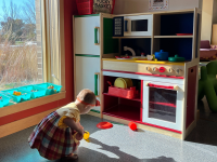 Toddler playing with a colorful play kitchen